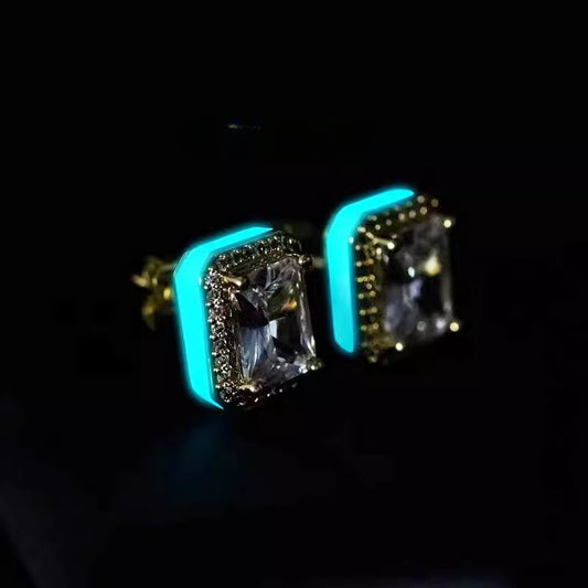 Pair of gold-tone rectangular halo stud earrings with glowing aqua side accents on a black background