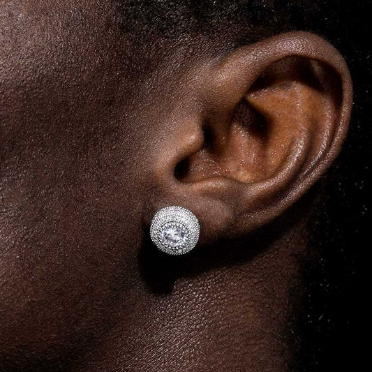 Silver-tone round halo stud earring with a clear center stone and layered border worn on an ear