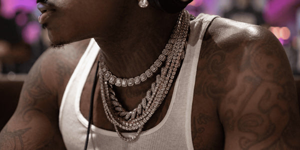 Man wearing layered Cuban link and tennis chains, illustrating different men’s chain styles and how they look when stacked.