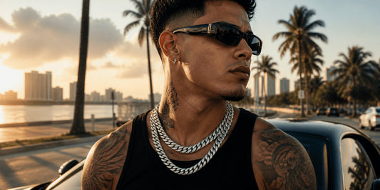 IceGrind Latino male model wearing two silver miami cuban link chains on a Miami coastal road at sunset, featuring modern hip hop jewelry styling and urban streetwear aesthetics.