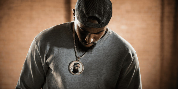 Man wearing a large round picture pendant with an iced stone frame, showing the chest coverage of an oversized custom photo pendant.