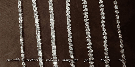 Macro photo of seven distinct diamond tennis chains with bezel settings showcasing different cuts—emeralds, asschers, radiants, marquises, pears, hearts, and ovals—laid out and labeled on dark velvet. An iced-out showcase by icegrind.