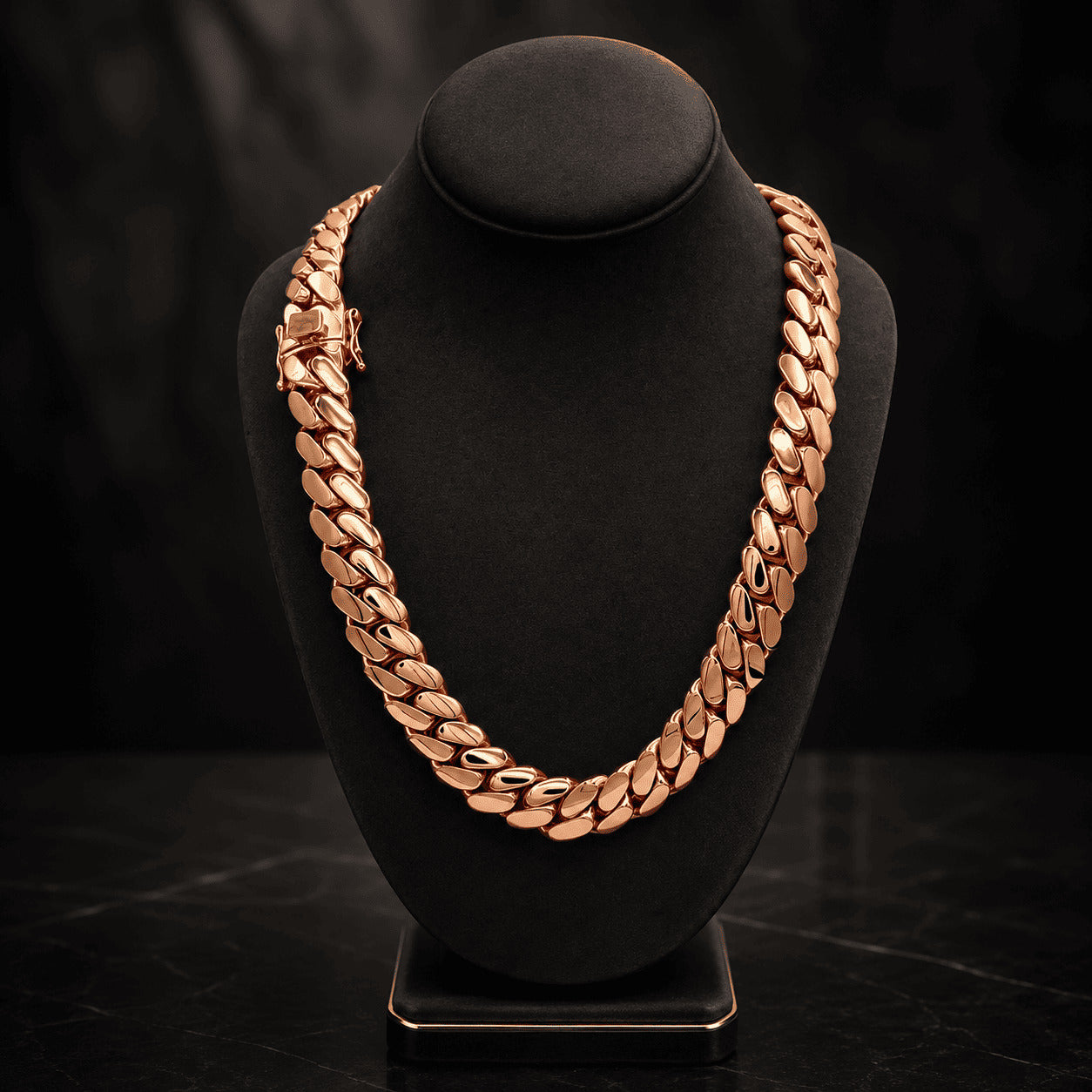 16MM rose gold Miami Cuban link chain draped over a black display bust on a dark surface with its box clasp visible