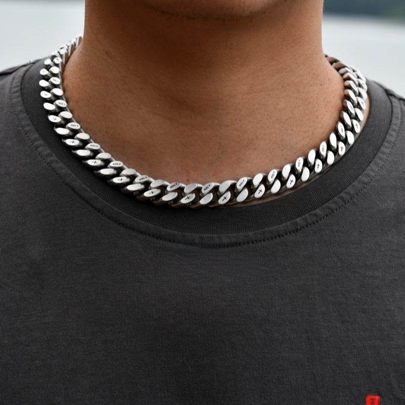 white gold Miami Cuban link chain worn around the neck in a blurred outdoor setting