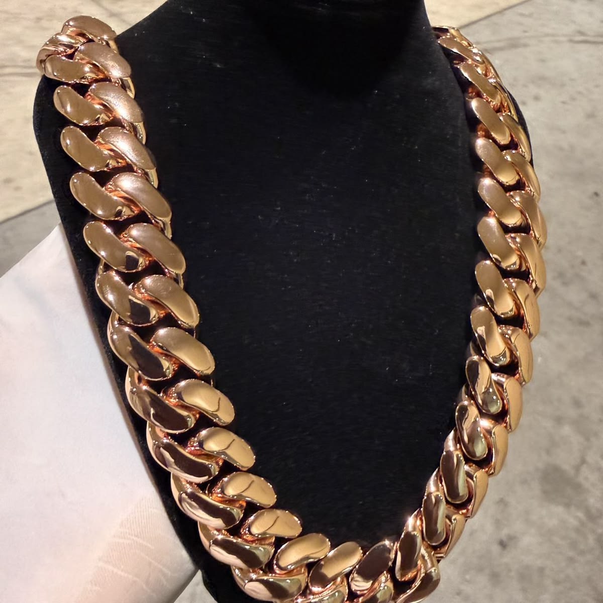 20MM rose gold Miami Cuban link chain draped over a black display bust with its box clasp visible