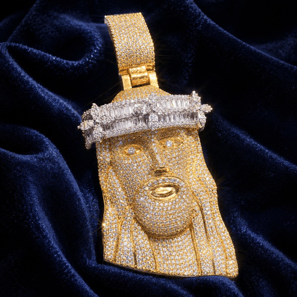 Premium yellow gold Iced Out Baguette Crown Jesus Piece laid flat on luxurious blue velvet fabric.