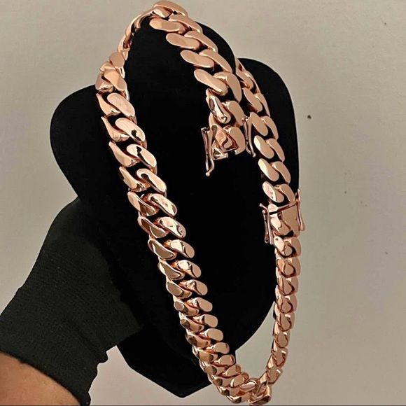 Coiled 20MM rose gold Miami Cuban link chain on a stand with its box clasp visible