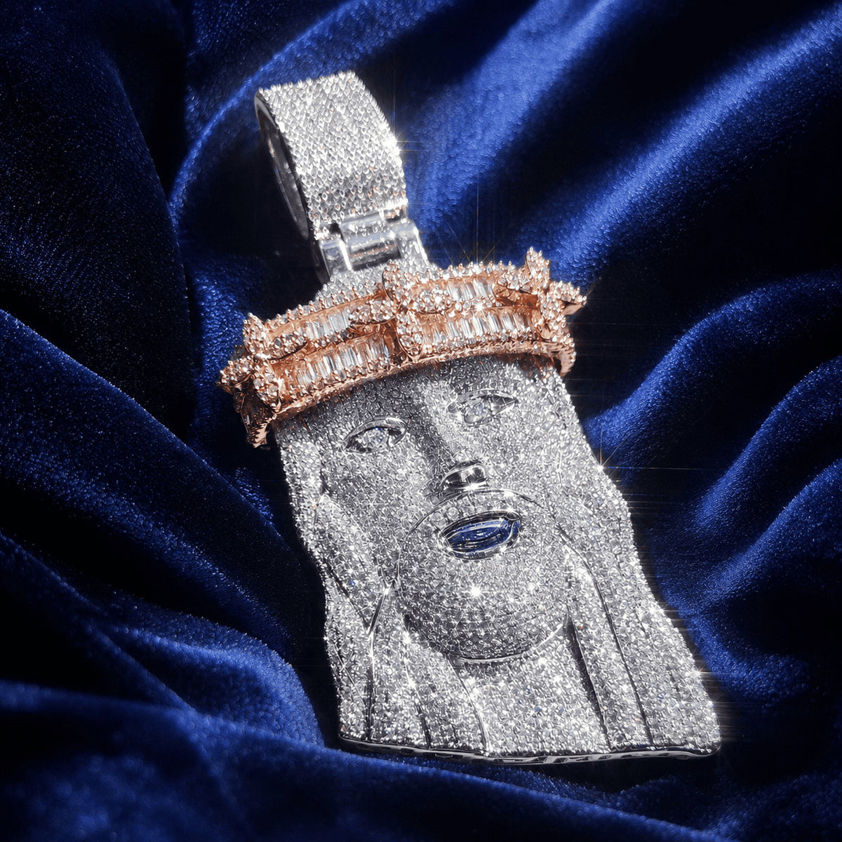 Silver-tone and rose gold Iced Out Baguette Crown Jesus Piece crafted with bright cubic zirconia resting on blue velvet.