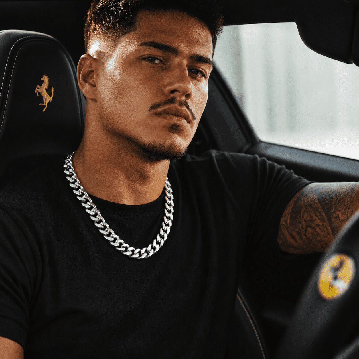 Lifestyle photo of a man in a luxury car wearing the IceGrind 12MM cuban link miami chain, representing a bold, high-end street style.