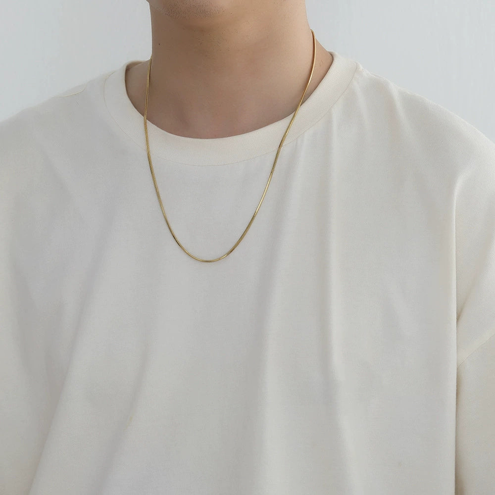 2MM gold snake chain worn around the neck against a white background