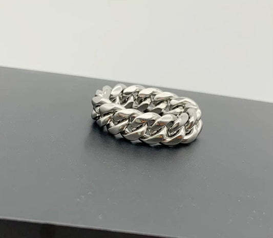 Close-up of a single silver-tone Cuban link ring lying flat on a dark surface