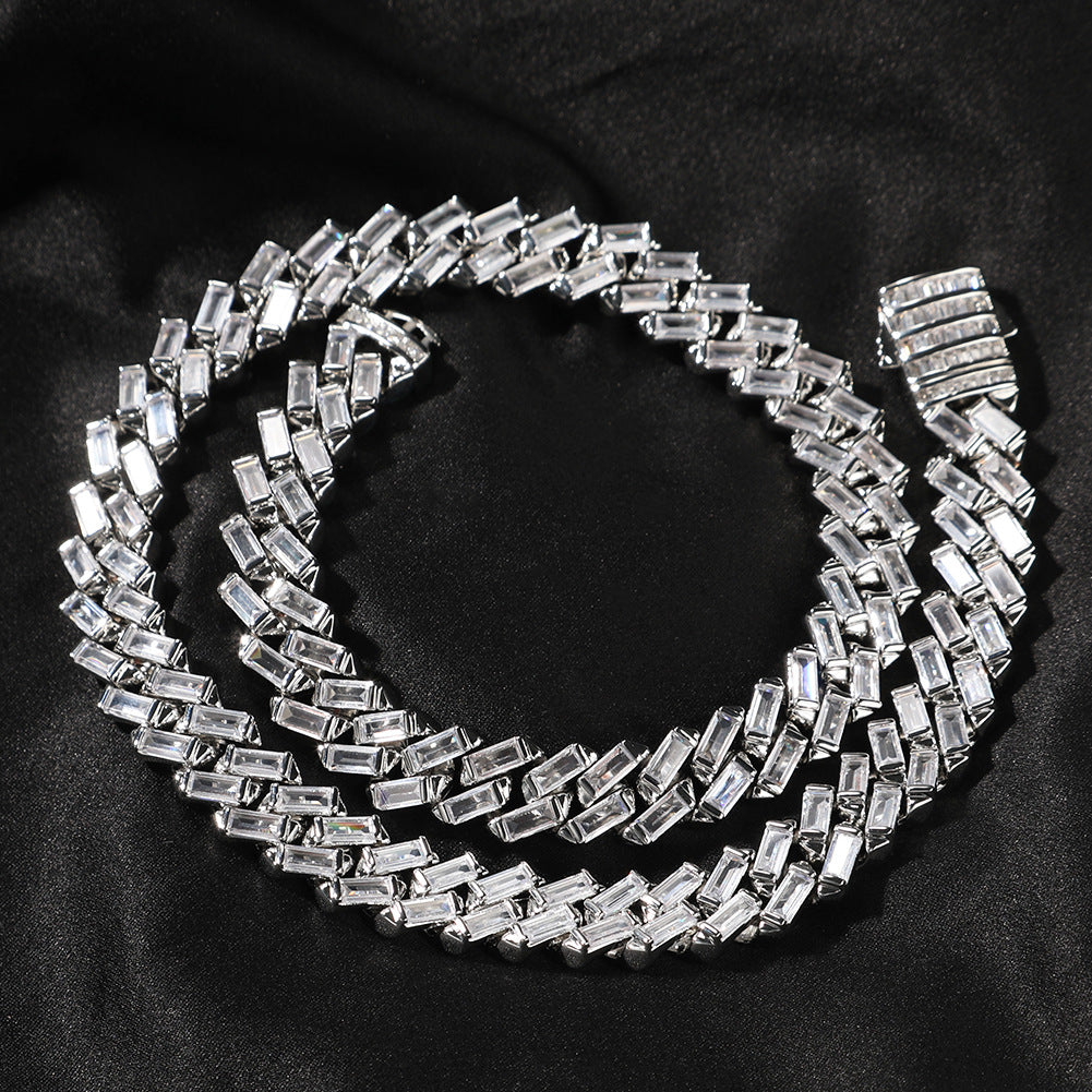 Coiled 12MM white gold Cuban link chain on a dark textured surface with its box clasp visible