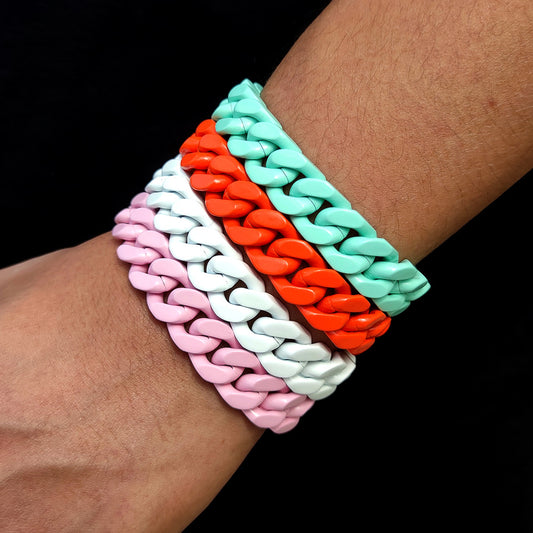 Four stacked chain-link bracelets in pink, white, orange, and teal on a wrist, close-up view