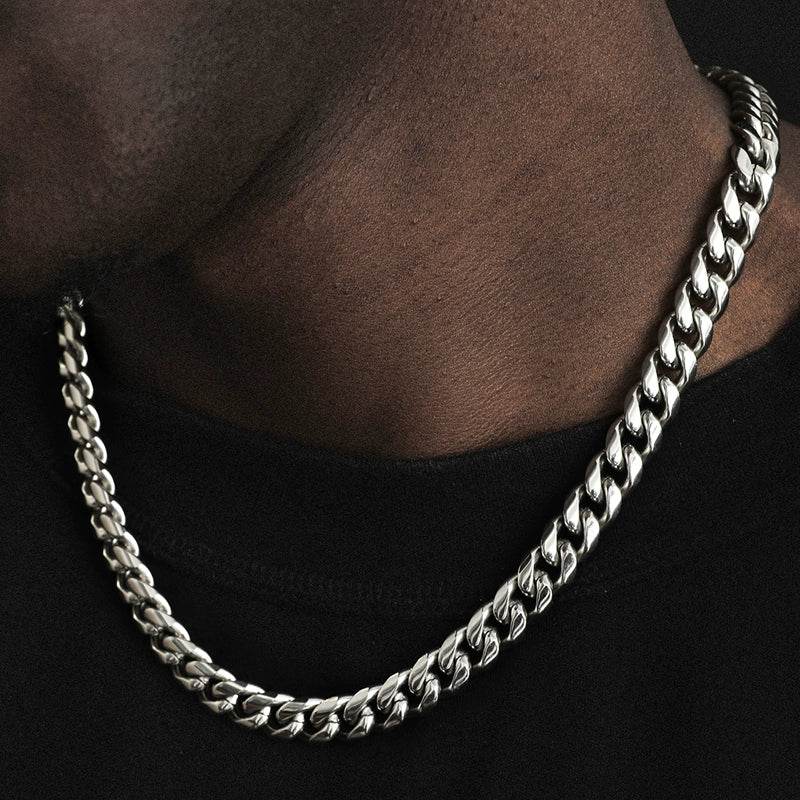 white gold Miami Cuban link chain worn around the neck over dark clothing