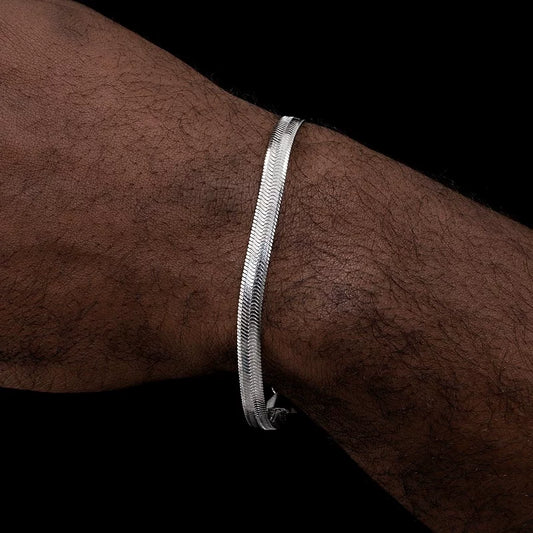 Silver-tone flat herringbone bracelet worn across a wrist against a black background