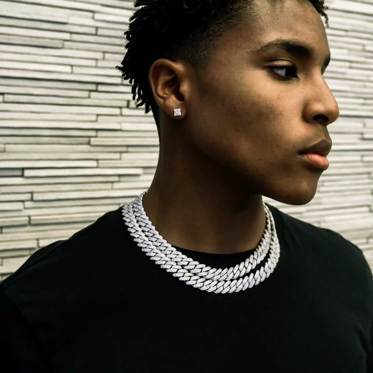 14MM white gold Cuban link chain worn around the neck on a model for fit and style against a textured wall