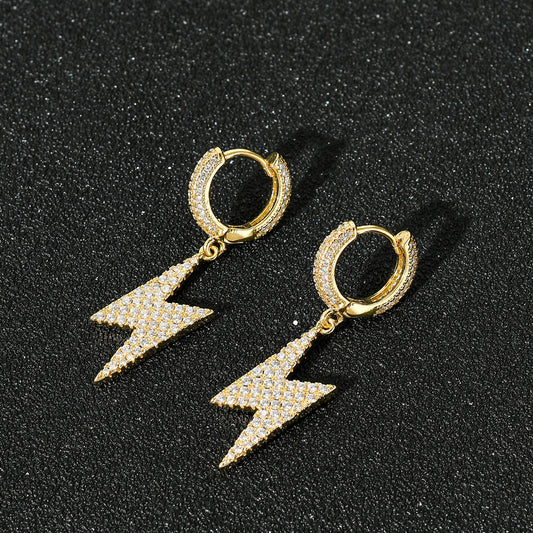 Closed pair of gold-tone lightning bolt drop earrings with stone-covered hoops on black fabric