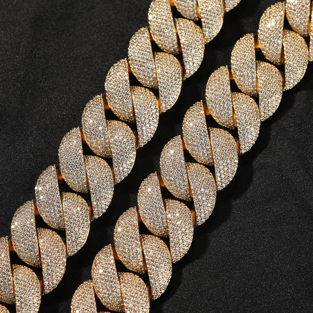 Coiled 24MM gold Cuban link chain on a dark textured surface