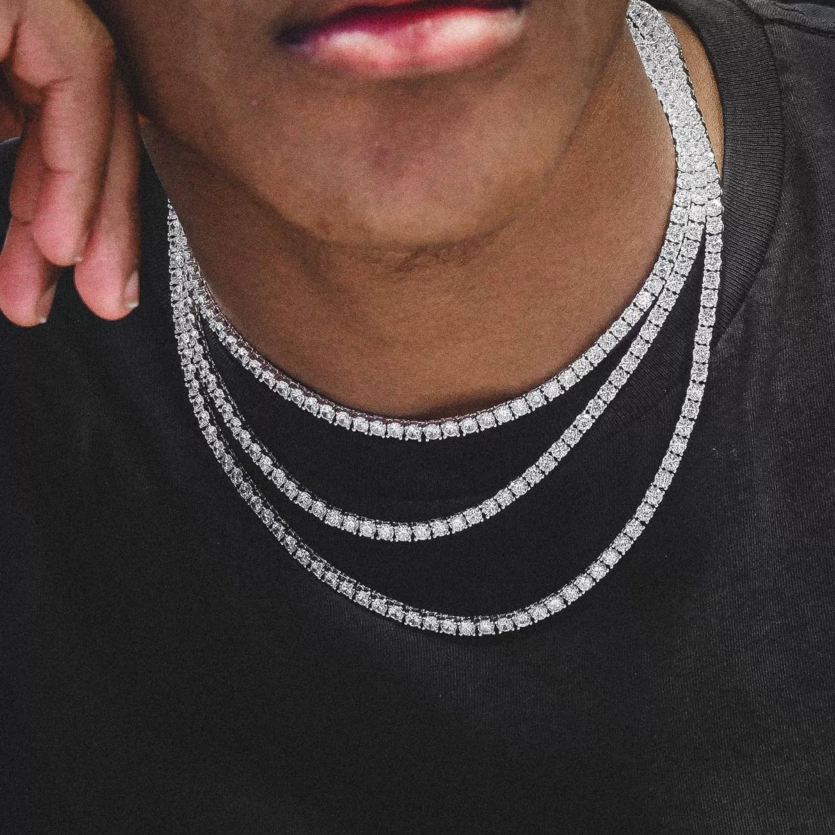 Layered tennis chain worn around the neck over a black top