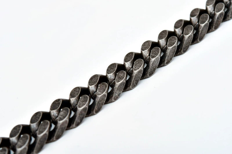 Close-up of 12MM black Cuban link chain links laid flat against a white background
