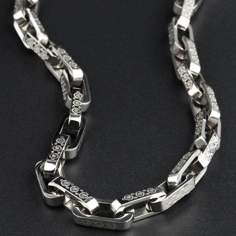 Curved white gold chain with overlapping links on a dark neutral surface