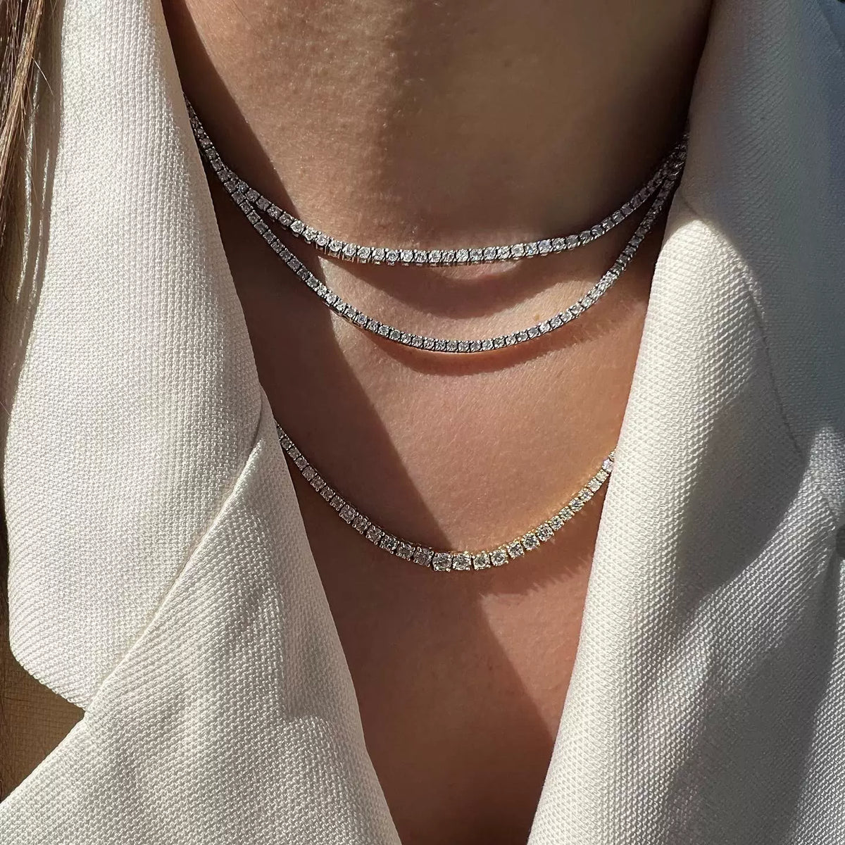 Layered tennis chain worn around the neck against a white background