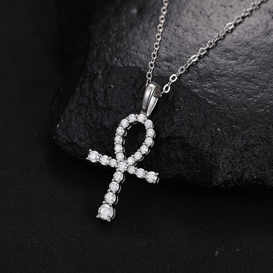 Silver-tone ankh pendant with clear stones on a fine chain against a dark stone surface