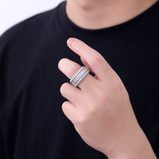 Close-up of a hand wearing three stacked silver-tone band rings with full stone coverage
