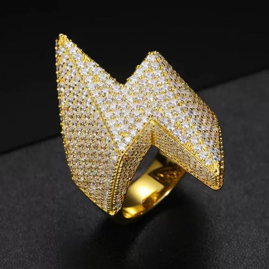 Close-up of a gold-tone lightning ring with full clear stone coverage, shown upright on a dark surface