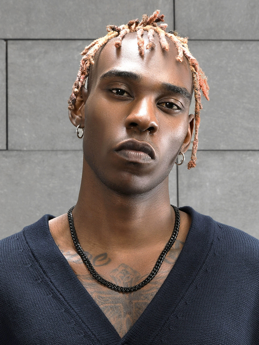 8MM black Cuban link chain worn around the neck on a model near a gray tiled wall