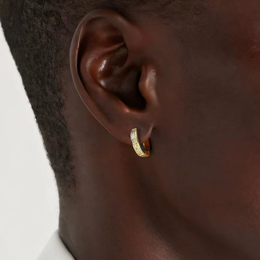 Gold-tone huggie hoop earring with a stone-covered front and aqua inner edge worn on an ear