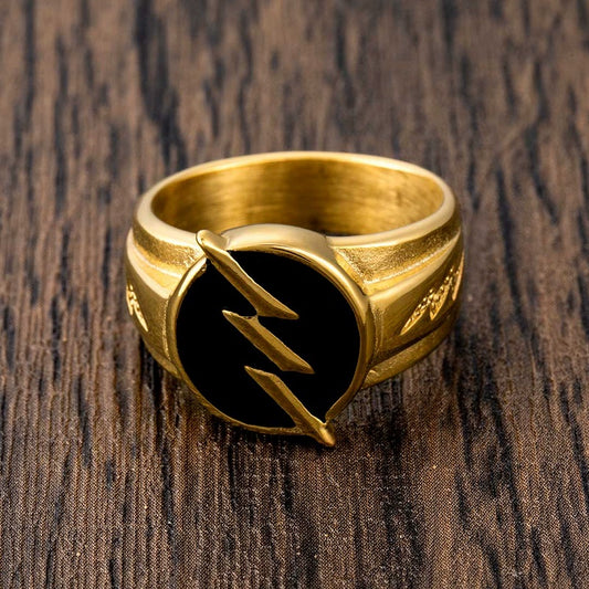 Top-down view of a gold-tone signet ring with a black round face and lightning bolt motif on wood
