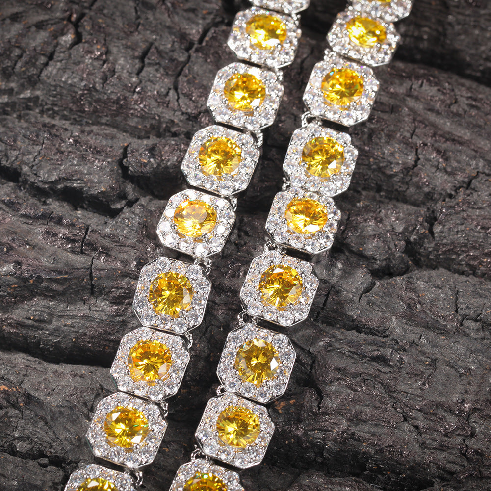 Close-up of 12MM gold tennis chain links laid flat on a dark textured surface
