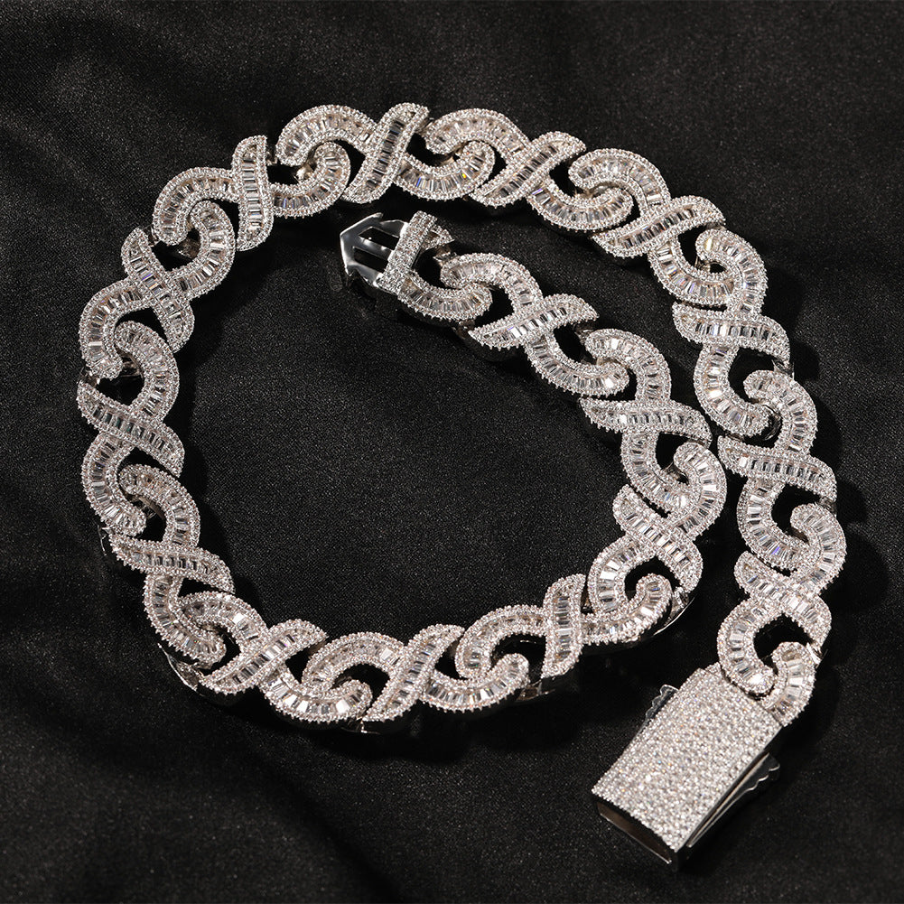 Coiled 15MM white gold Cuban link chain on a dark textured surface with its box clasp visible