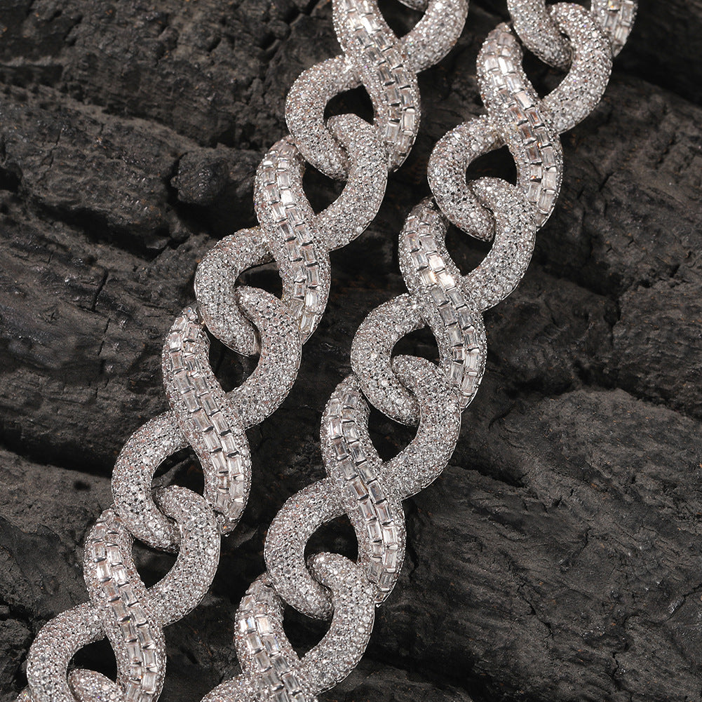 Close-up of 16MM white gold Cuban link chain links laid flat on a dark textured surface