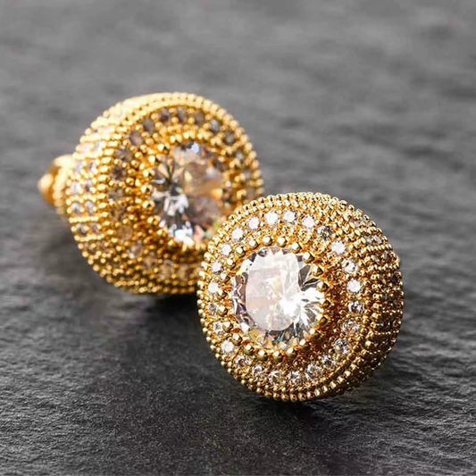 Angled pair of gold-tone round halo stud earrings with clear center stones and concentric stone borders