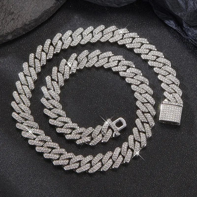 Coiled 14MM white gold Cuban link chain on a dark textured surface with its box clasp visible